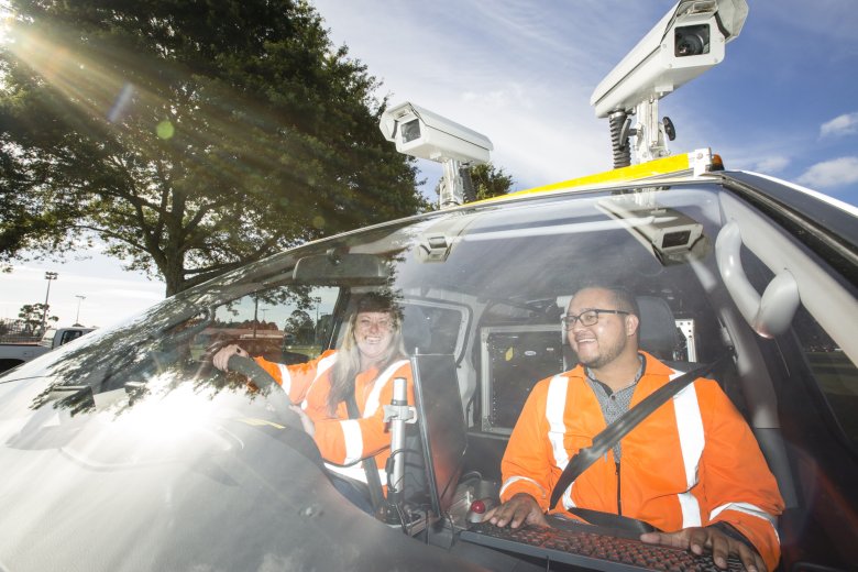 Geospatial team in car smiling at camera