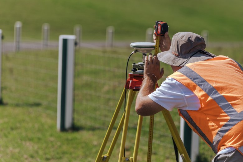 Surveyor measuring distances of tripod device with tape measure