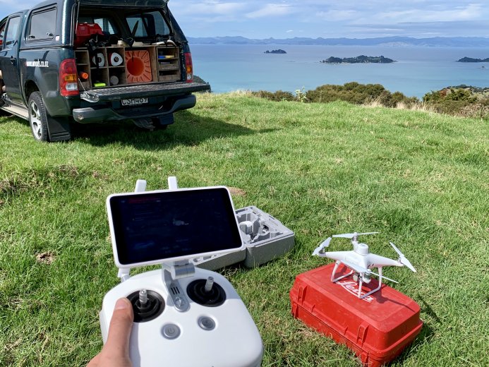 UAV ready for take off on grass with operators hand holding controller in foreground