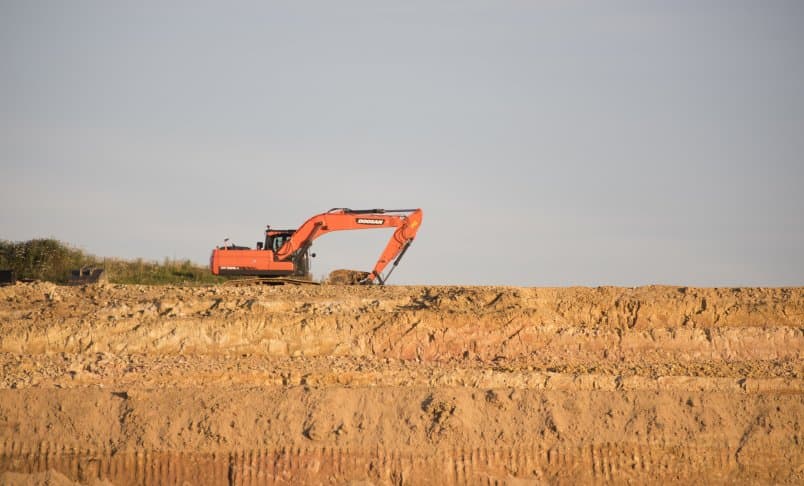 Image of earth moving machine on top of a clay bank
