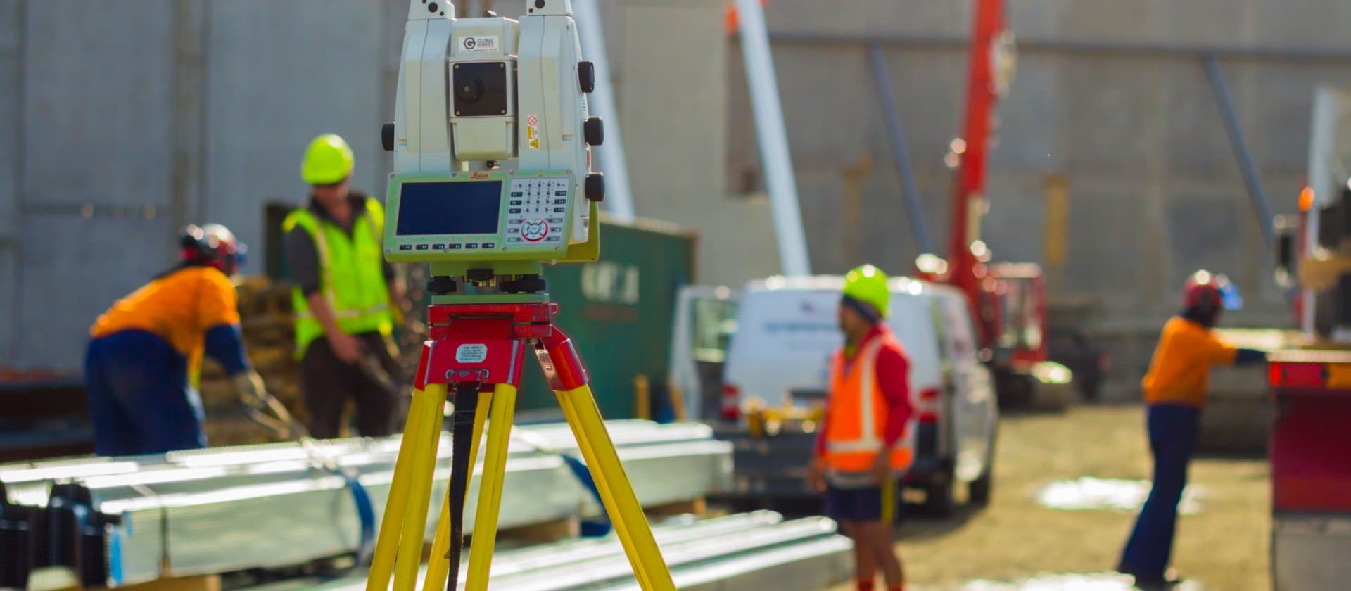 Image of surveying device on a tripod in the foreground and construction works in the background
