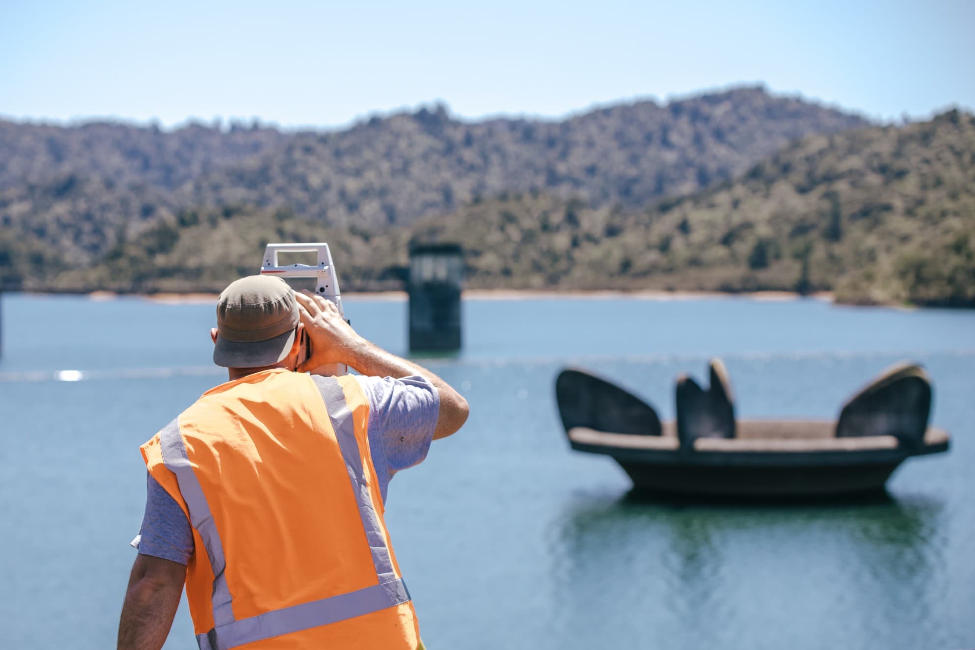 Image of person using a surveying device and looking over the dam